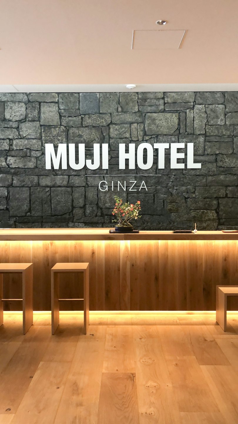 Hotelrezeption mit Holztresen und grauer Steinwand.