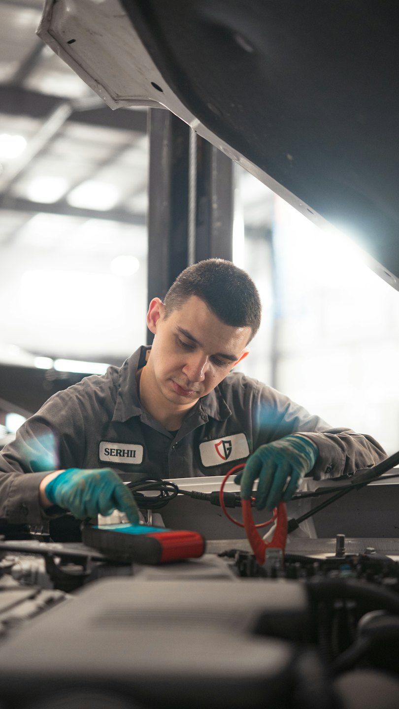 Mechaniker benutzt Diagnosegerät an Autowagenmotor in Werkstatt.